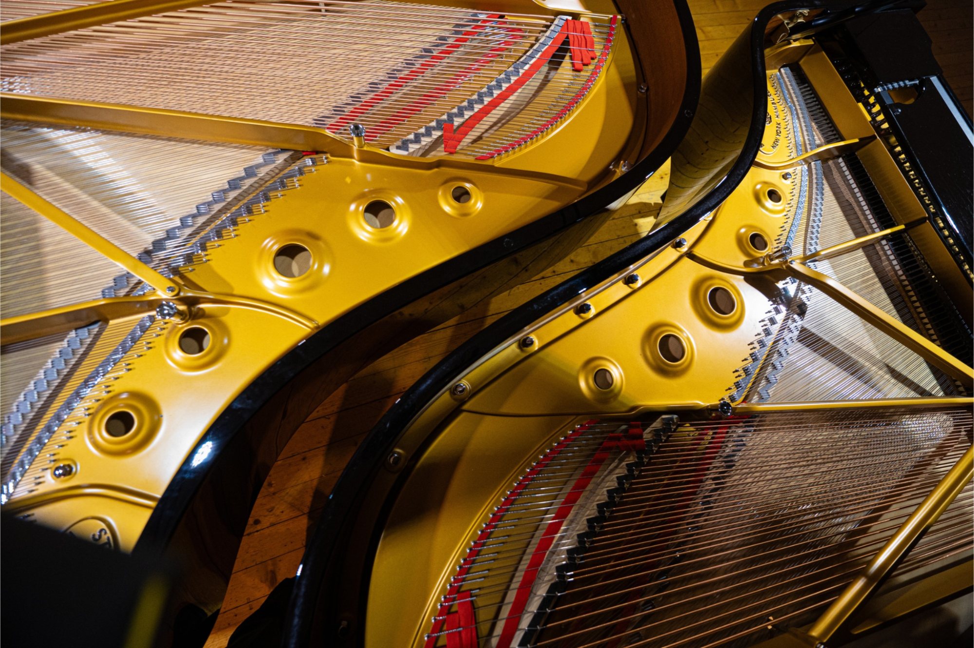 La table d'harmonie dorée et les cordes d'un piano de concert, vues de dessus